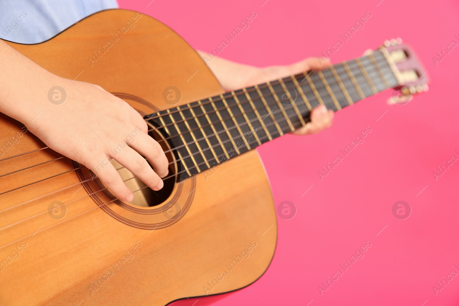 Photo of Little girl playing wooden guitar on color background, closeup