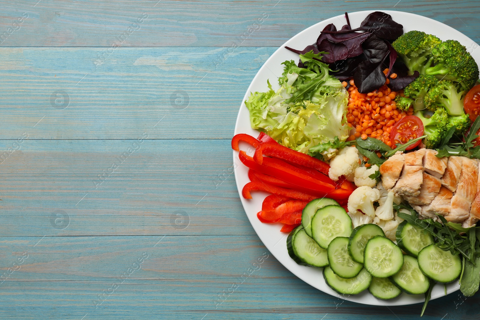 Photo of Balanced diet and healthy foods. Plate with different delicious products on light blue wooden table, top view. Space for text