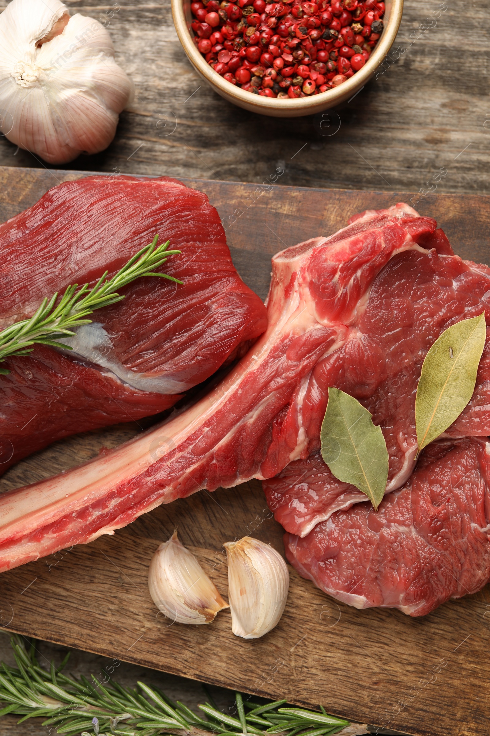 Photo of Pieces of raw beef meat and spices on wooden table, flat lay