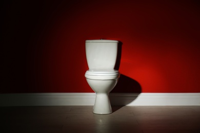 Photo of Toilet bowl near color wall in restroom. Space for text