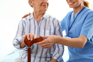 Nurse in uniform assisting elderly woman indoors, closeup