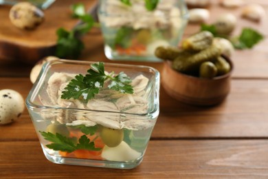 Delicious aspic with meat and vegetables served on wooden table, closeup. Space for text