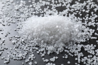 Heap of natural salt on black table, closeup