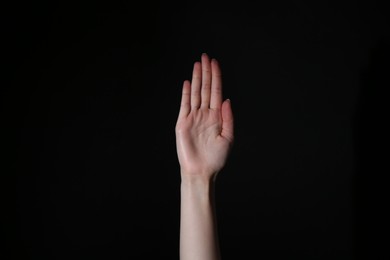 Woman showing open palm on black background, closeup