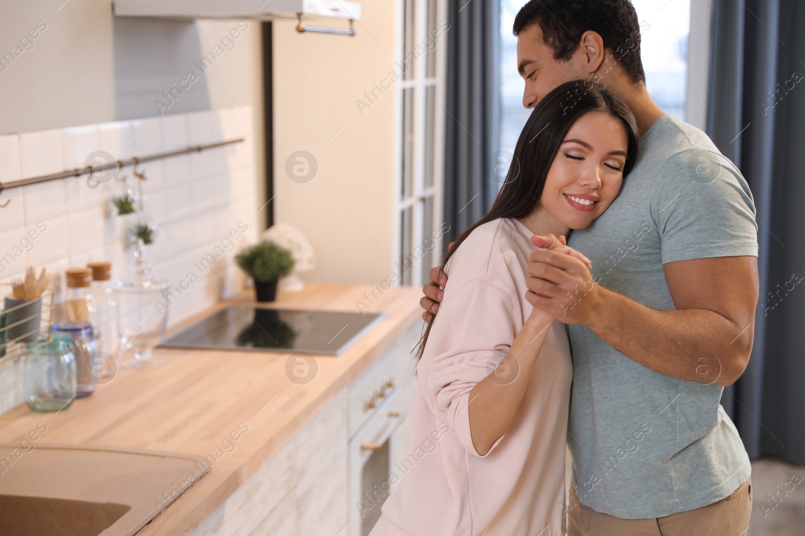 Photo of Lovely young interracial couple dancing at home. Space for text