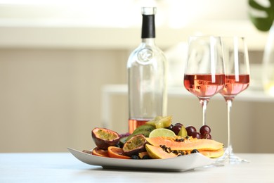 Photo of Delicious exotic fruits and wine on white table