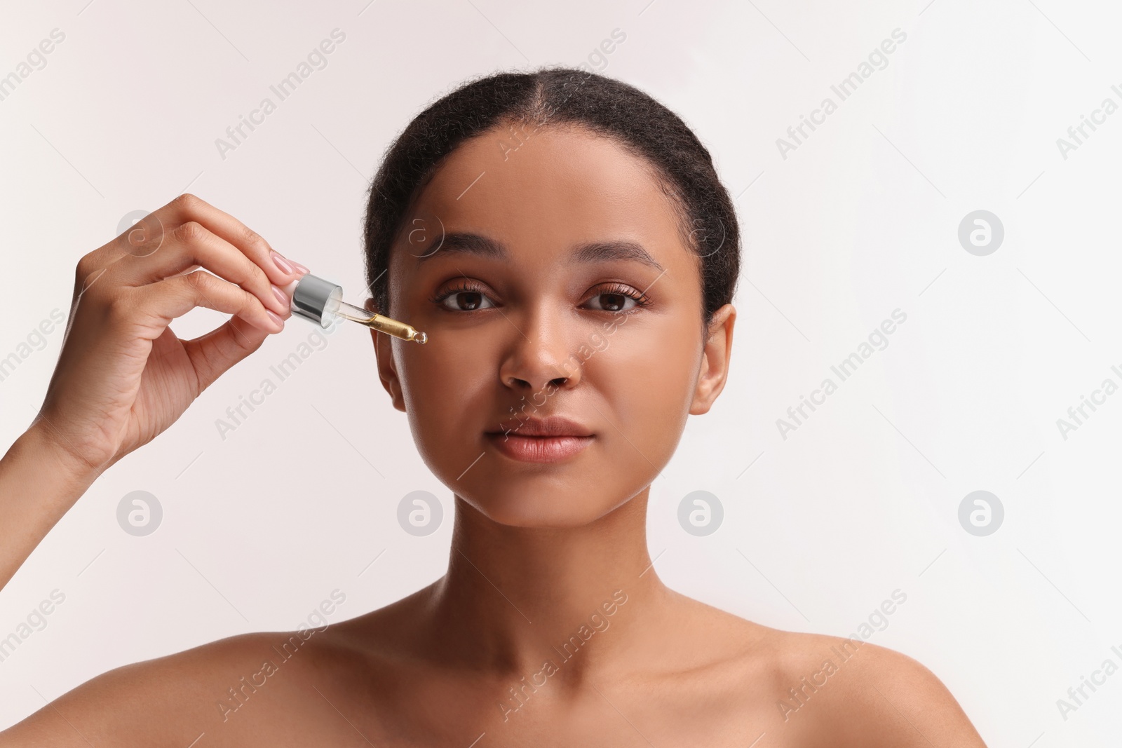 Photo of Beautiful woman applying serum onto her face on white background