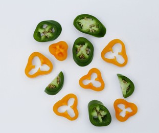 Photo of Different cut hot chili peppers on white background, flat lay