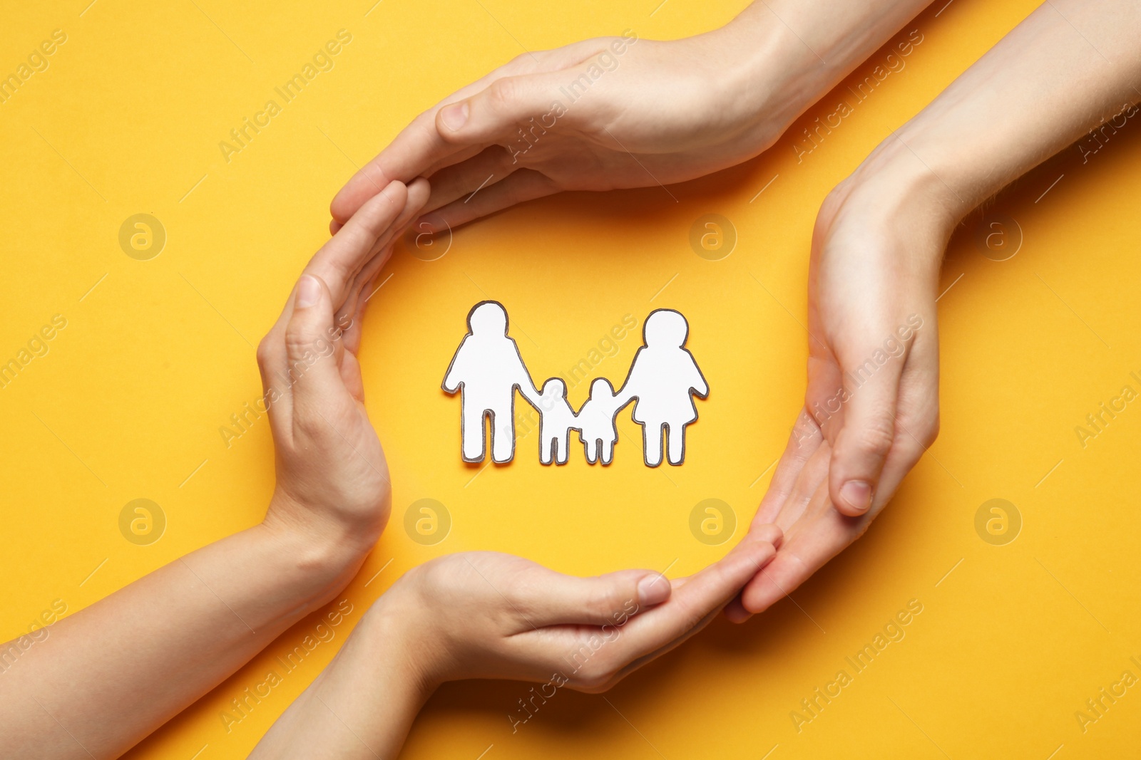 Photo of Couple with paper family cutout on yellow background, top view