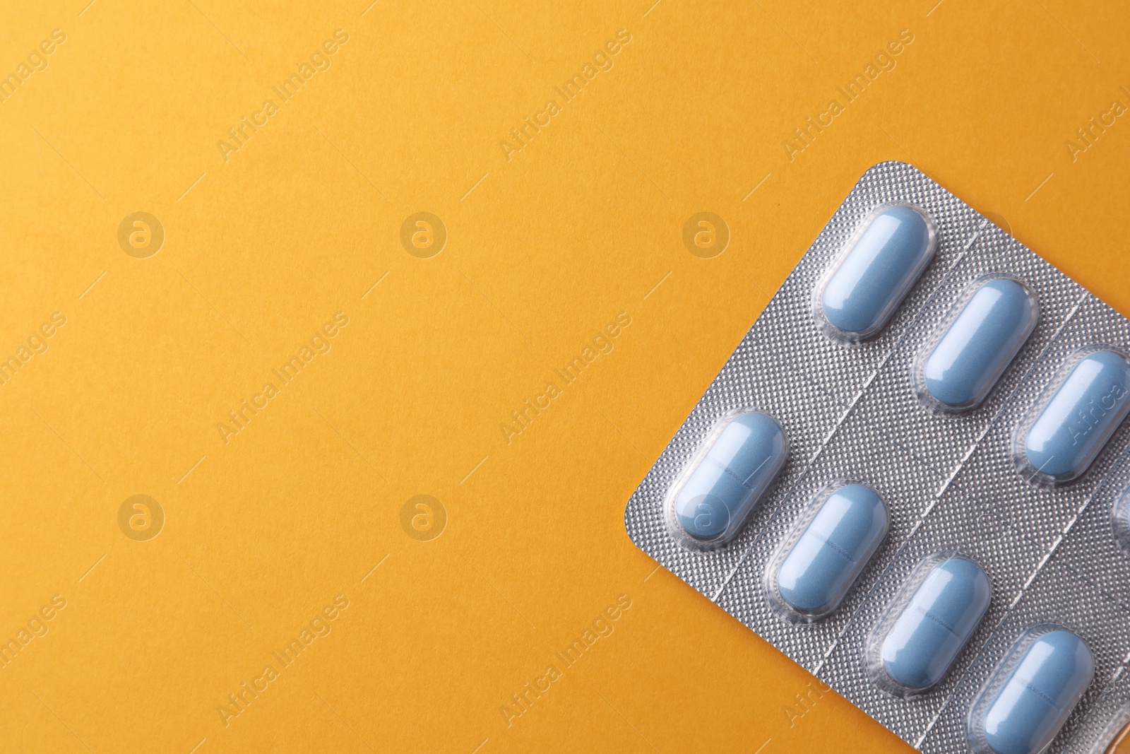 Photo of Pills and space for text on orange background, top view. Potency problem