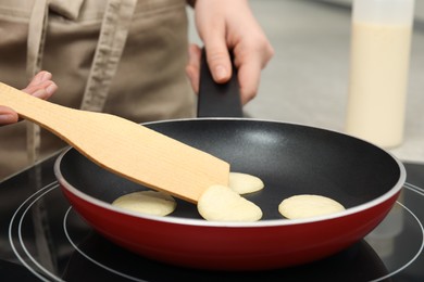Photo of Woman turning cereal pancake with spatula on stove, closeup