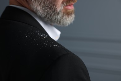 Photo of Bearded man with dandruff on his jacket against grey background, closeup. Space for text