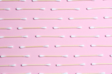 Many cotton buds on pink background, flat lay