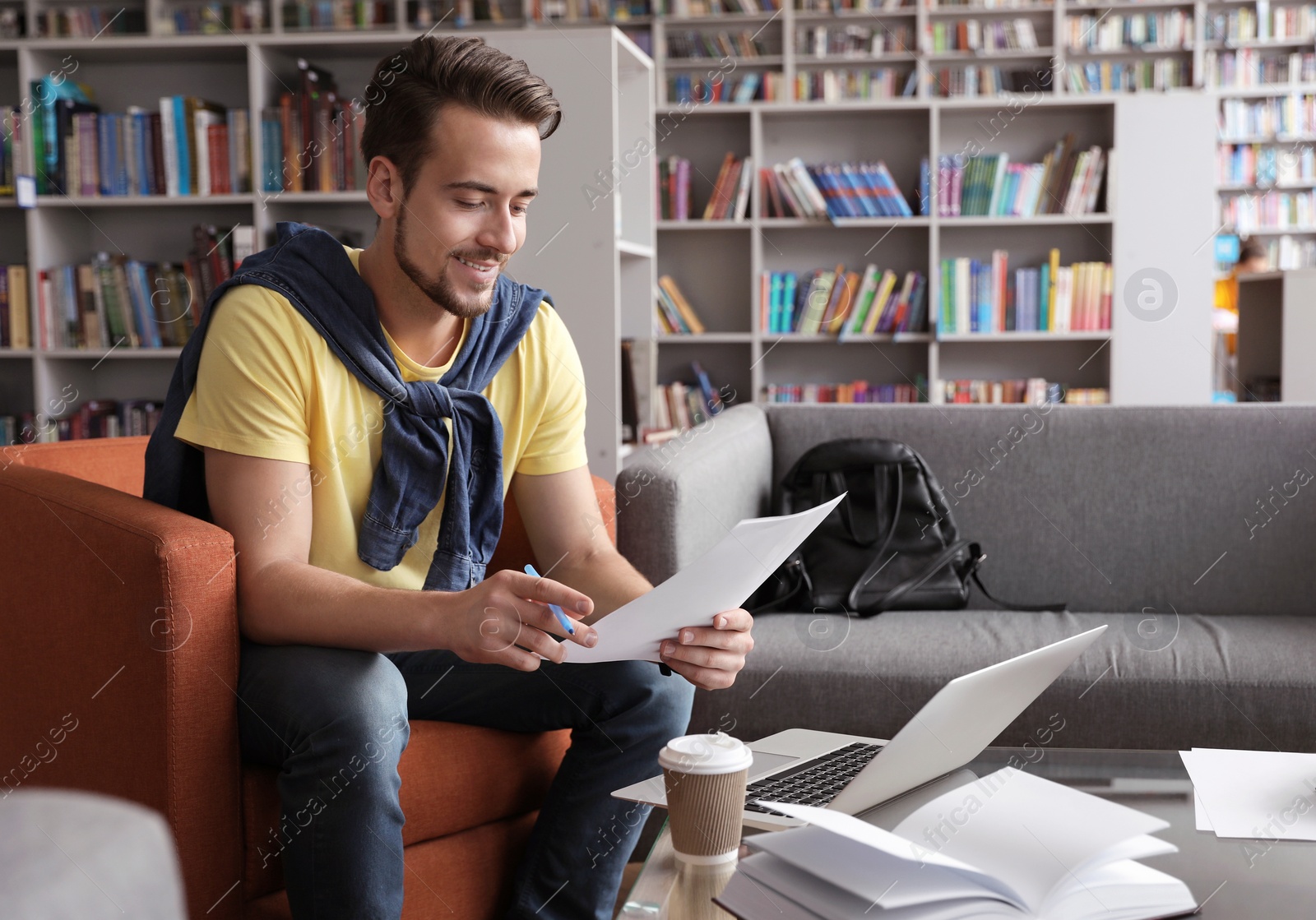 Photo of Young man studying at table in library