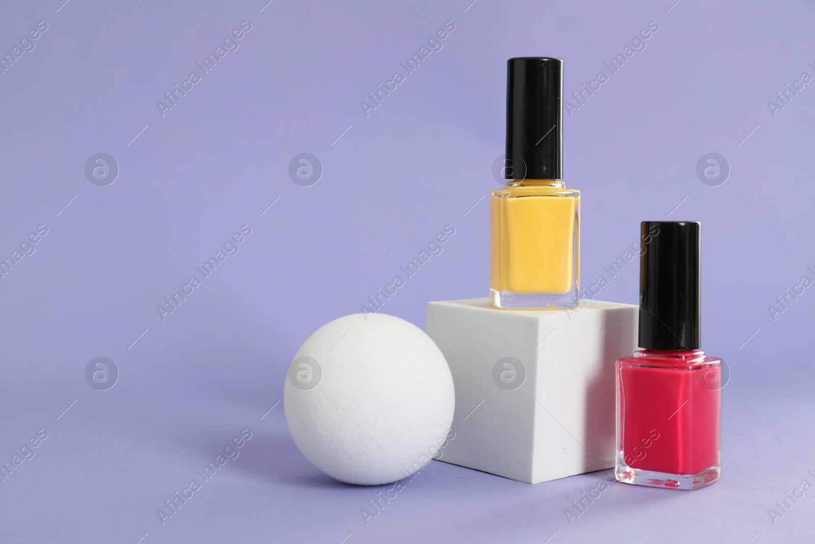 Photo of Stylish presentation of nail polishes on lilac background, space for text