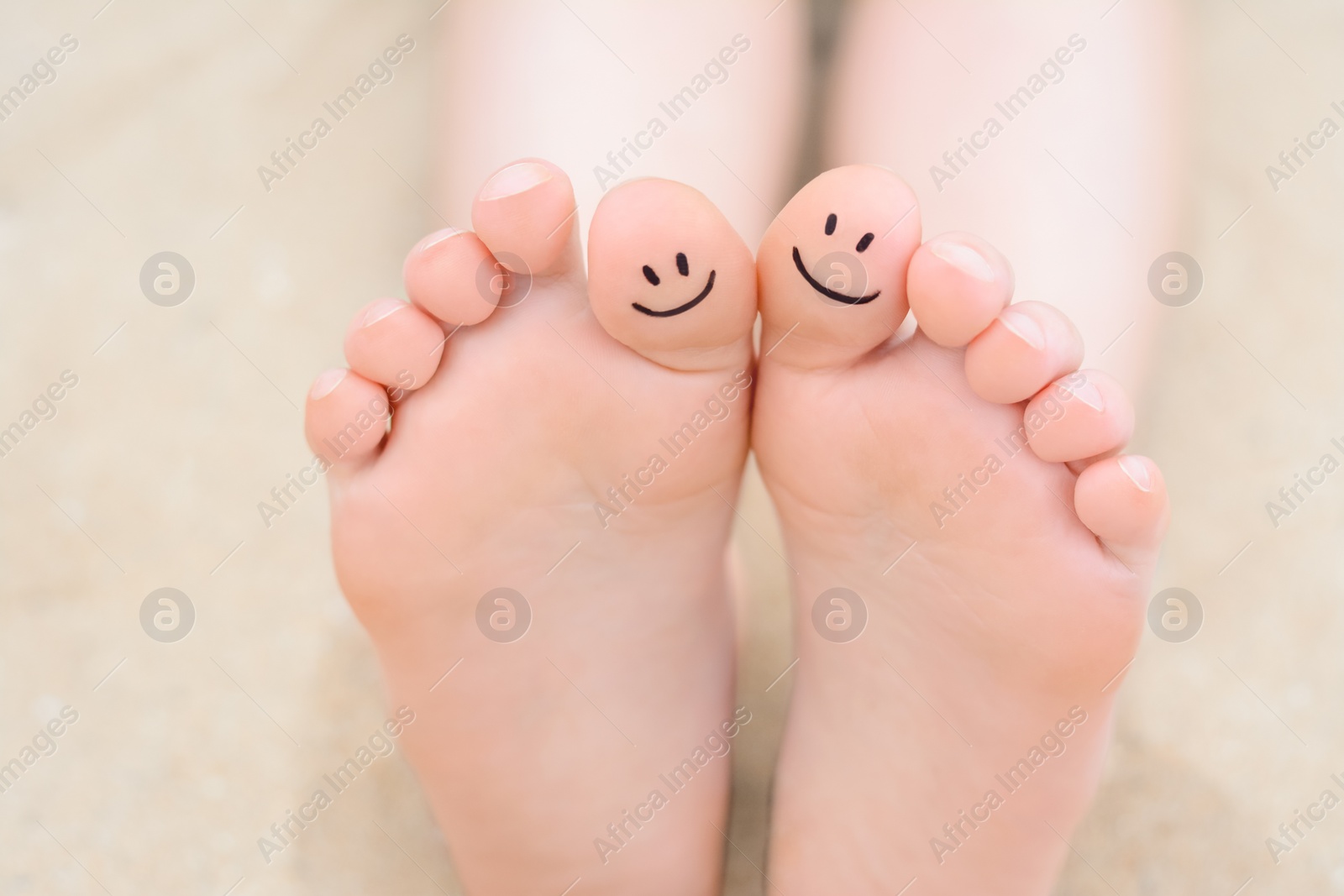 Photo of Woman with smiling faces drawn on toes, closeup of foot