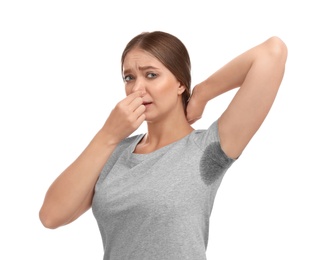 Young woman with sweat stain on her clothes against white background. Using deodorant