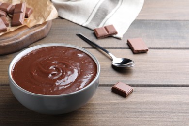 Photo of Delicious chocolate cream in bowl on wooden table, space for text