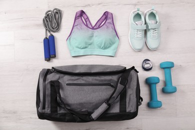 Photo of Grey bag and sports accessories on floor, flat lay