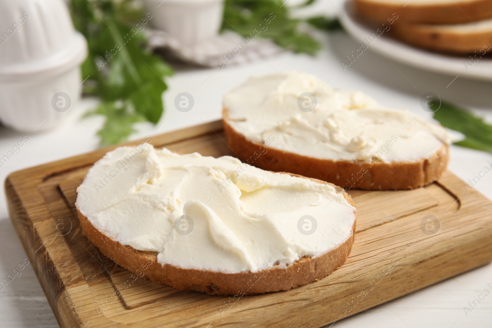 Photo of Bread with cream cheese on wooden table, closeup