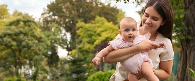 Happy mother with adorable baby in park on sunny day, space for text. Banner design 