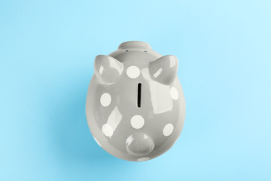 Grey piggy bank on light blue background, top view