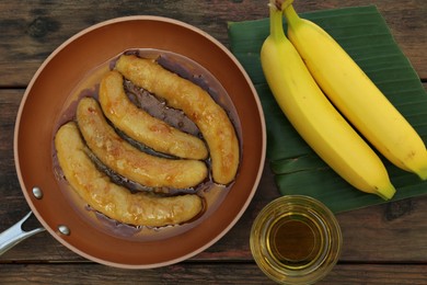 Delicious fresh and fried bananas with oil on wooden table, flat lay