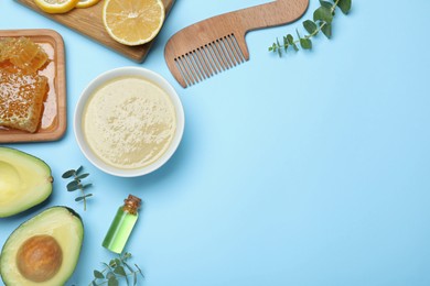Photo of Homemade hair mask in bowl, fresh ingredients and bamboo comb on light blue background, flat lay. Space for text