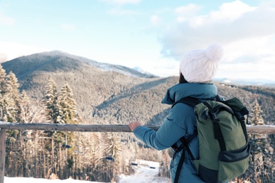 Woman with backpack enjoying mountain view during winter vacation. Space for text