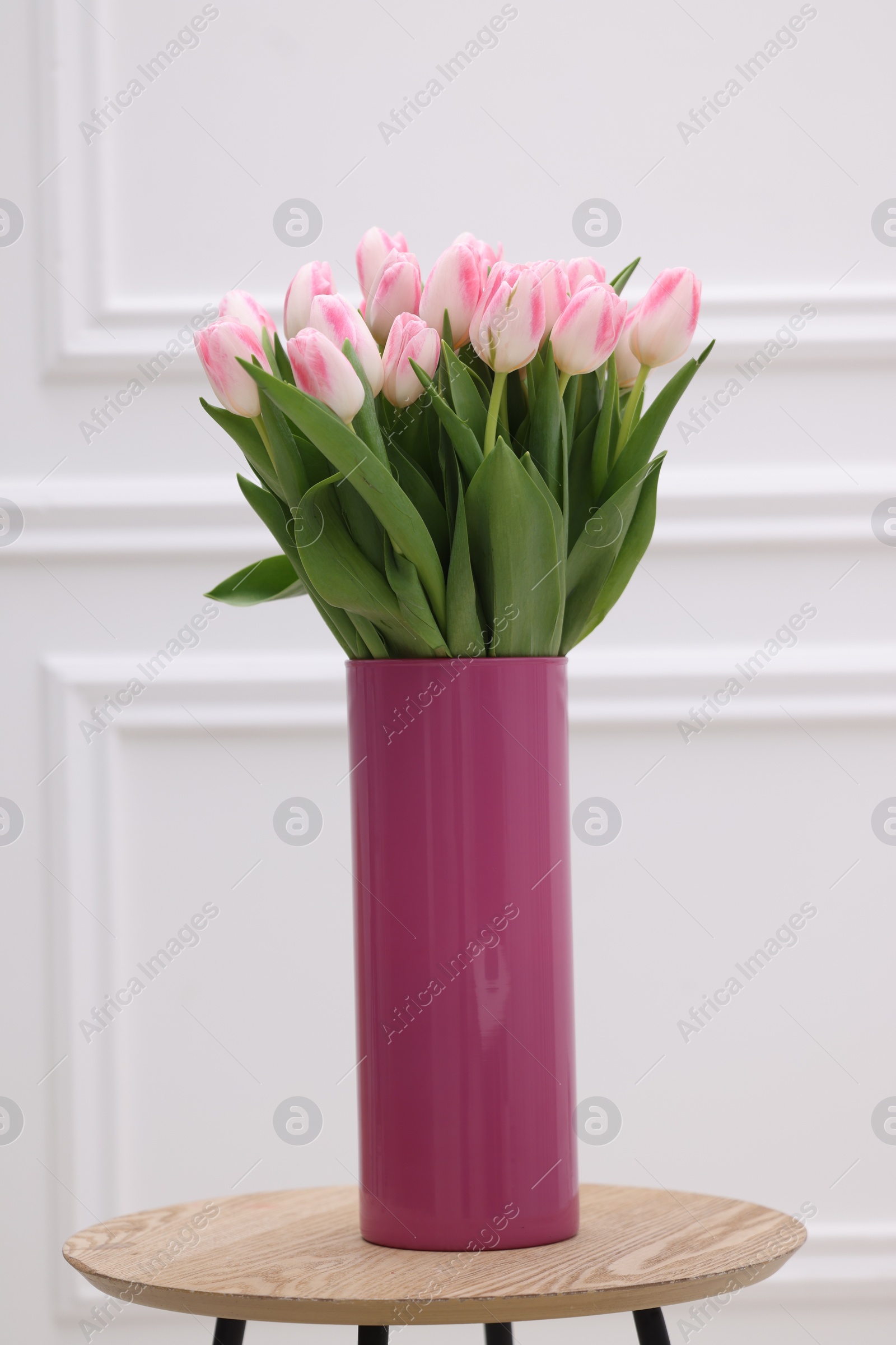 Photo of Beautiful bouquet of fresh pink tulips on table near white wall