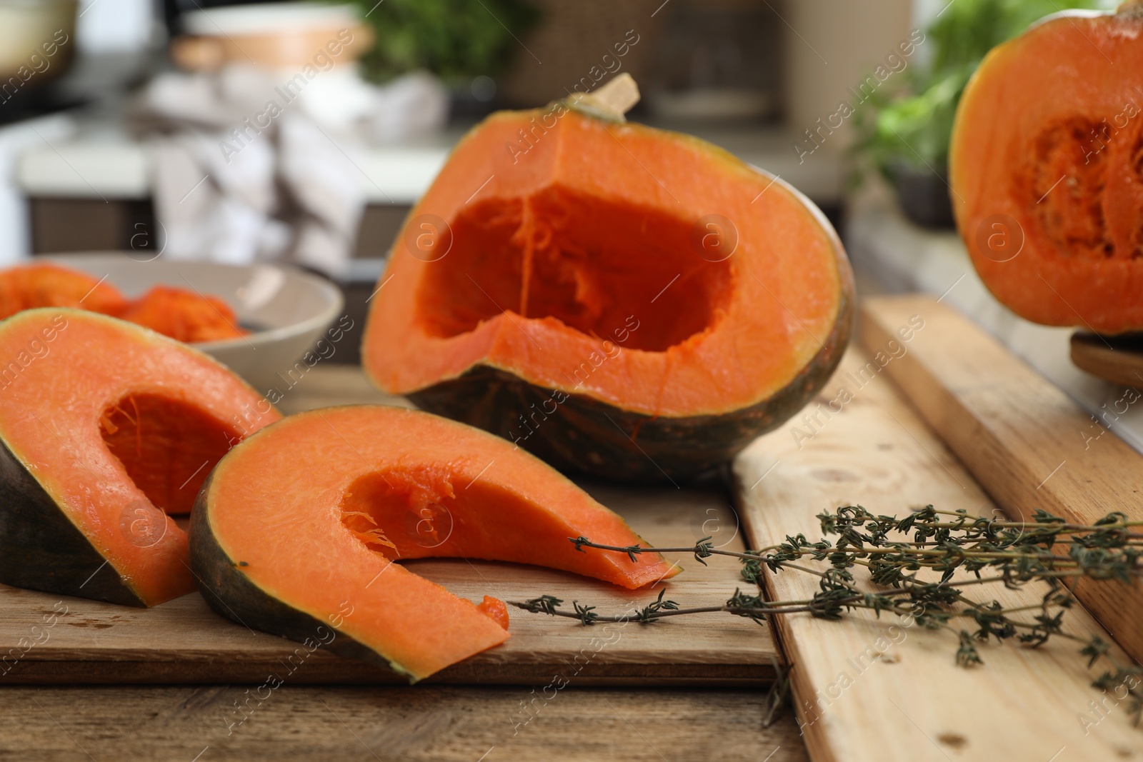 Photo of Cut fresh ripe pumpkin with aromatic thyme on wooden table in kitchen
