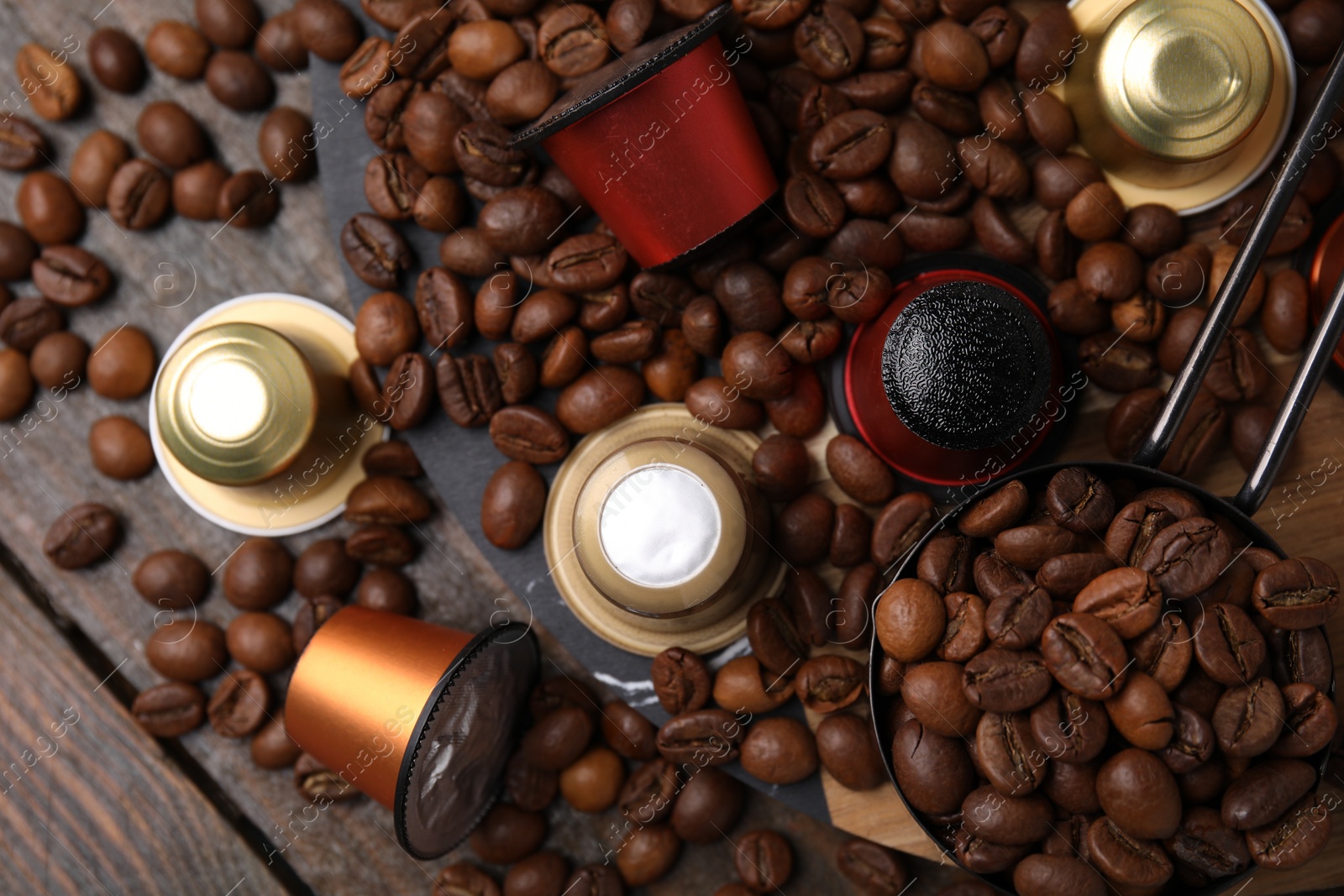 Photo of Saucepan with coffee capsules and beans on wooden table, flat lay
