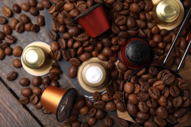 Photo of Saucepan with coffee capsules and beans on wooden table, flat lay