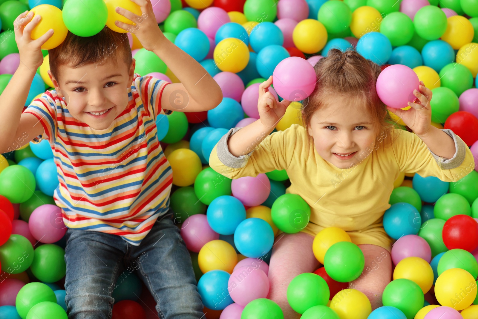 Photo of Cute little children playing in ball pit at indoor amusement park