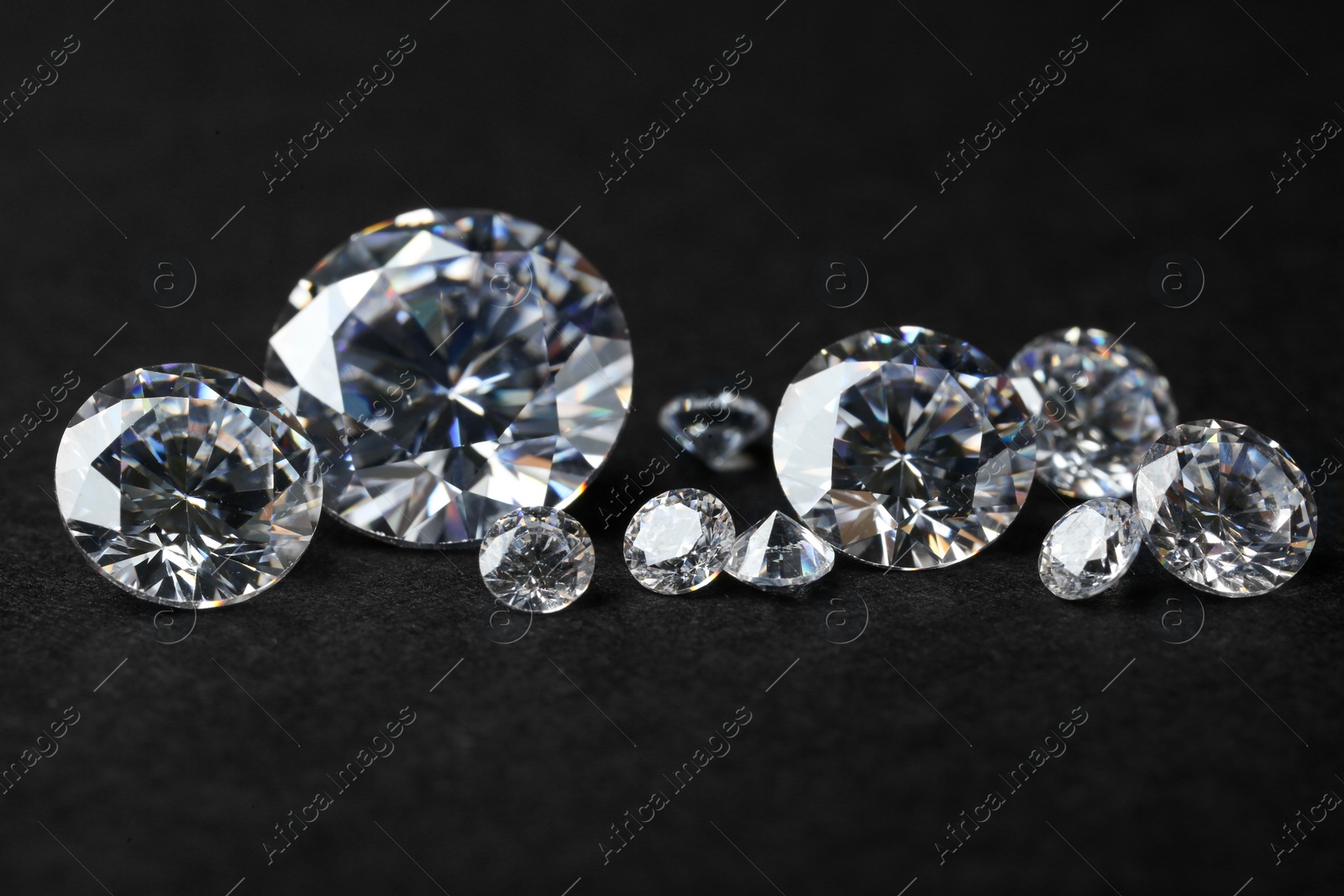 Photo of Many beautiful shiny diamonds on black background