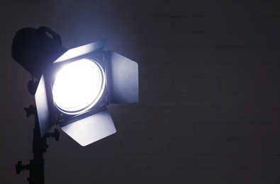 Photo of Professional photo studio lighting equipment near brick wall. Space for text