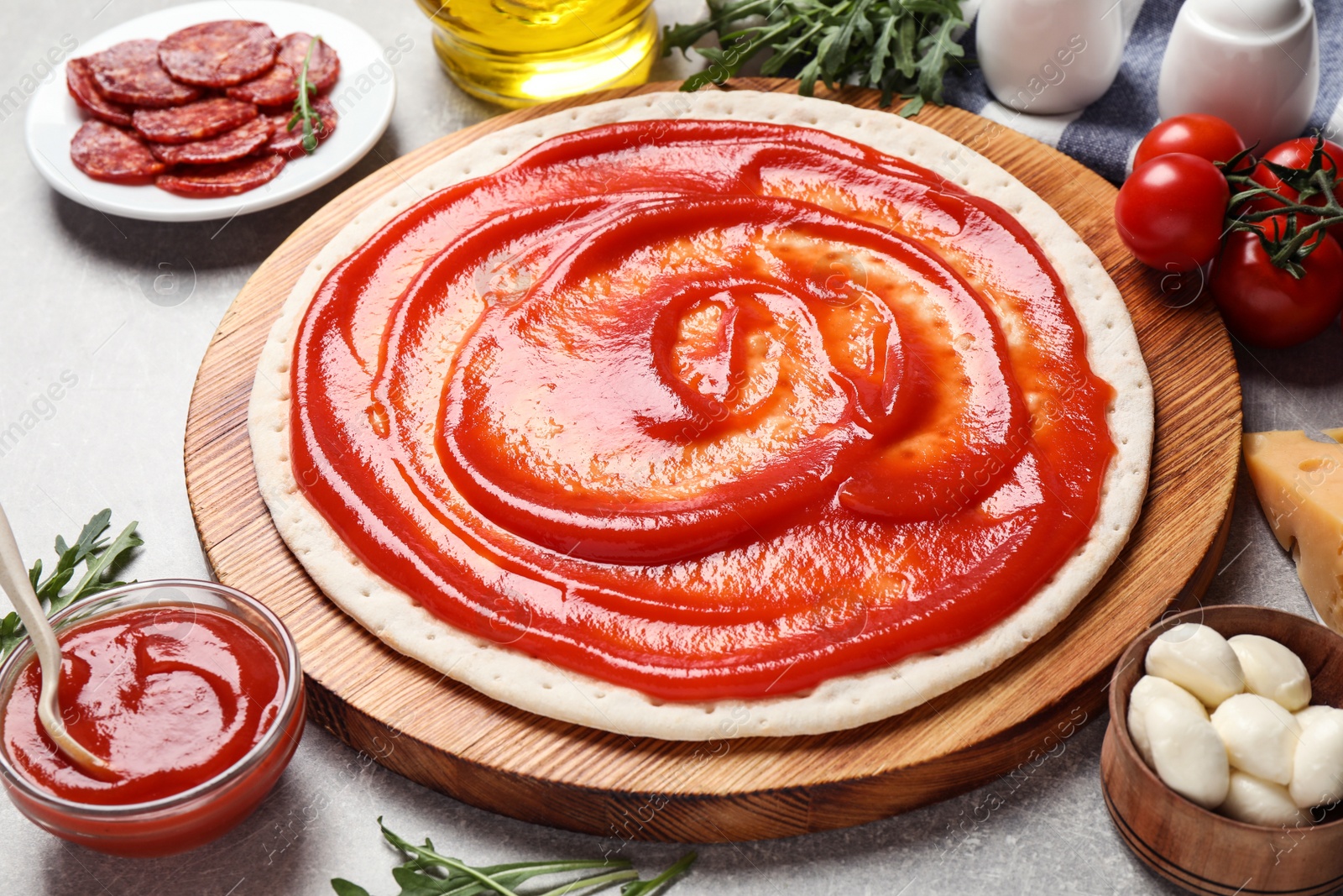 Photo of Base and fresh ingredients for pepperoni pizza on light grey table