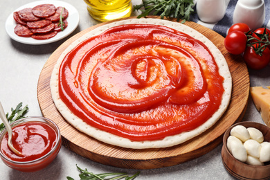 Photo of Base and fresh ingredients for pepperoni pizza on light grey table