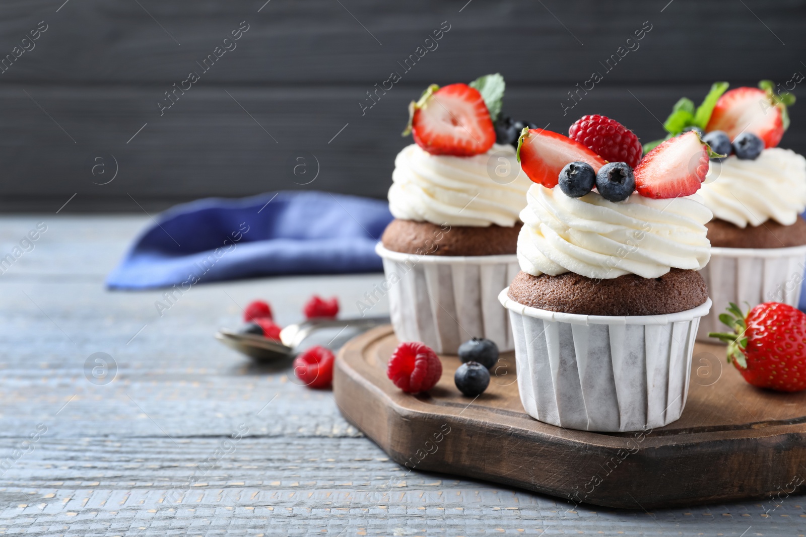 Photo of Sweet cupcakes with fresh berries on wooden table. Space for text