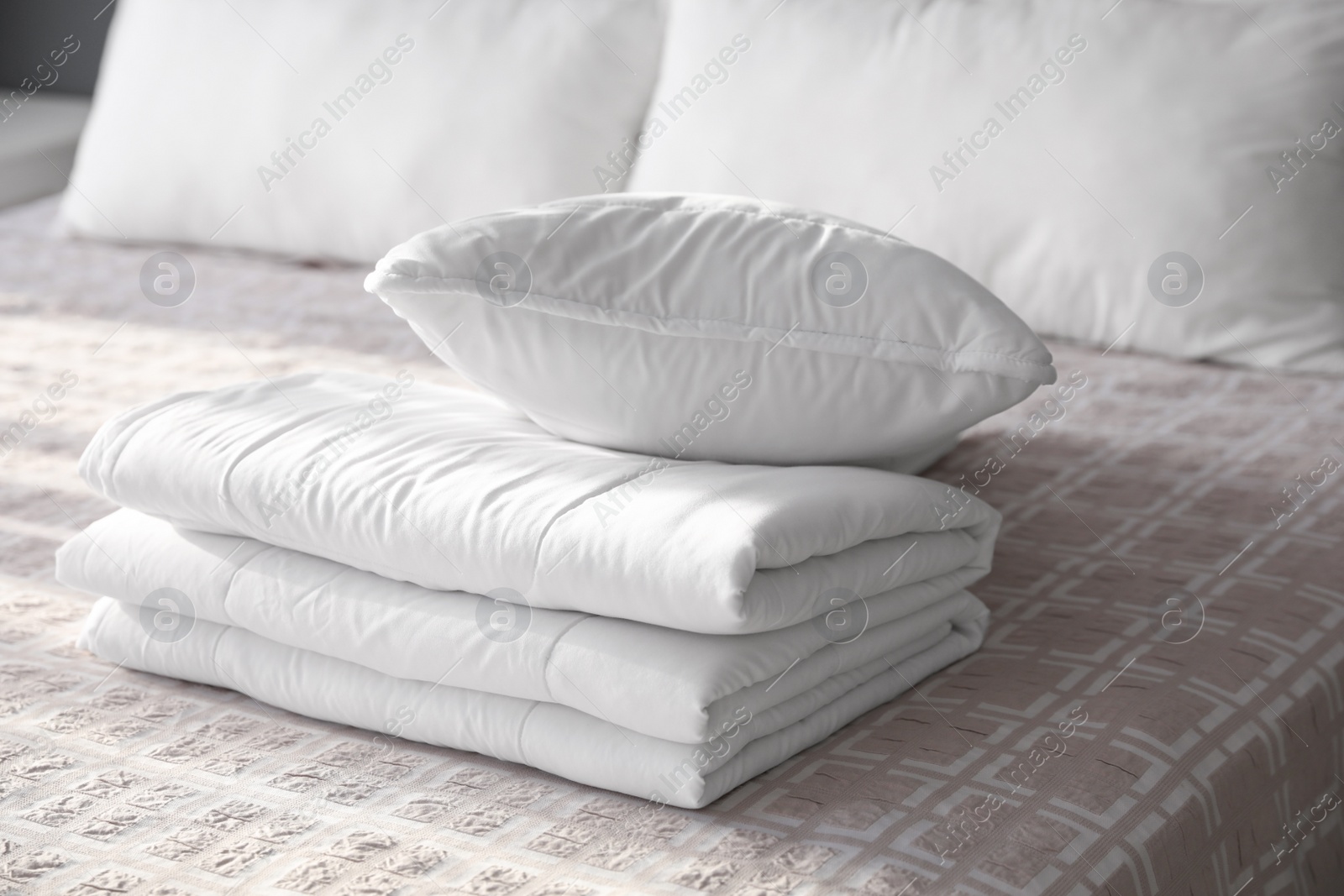Photo of Folded clean blanket and pillow on bed in room