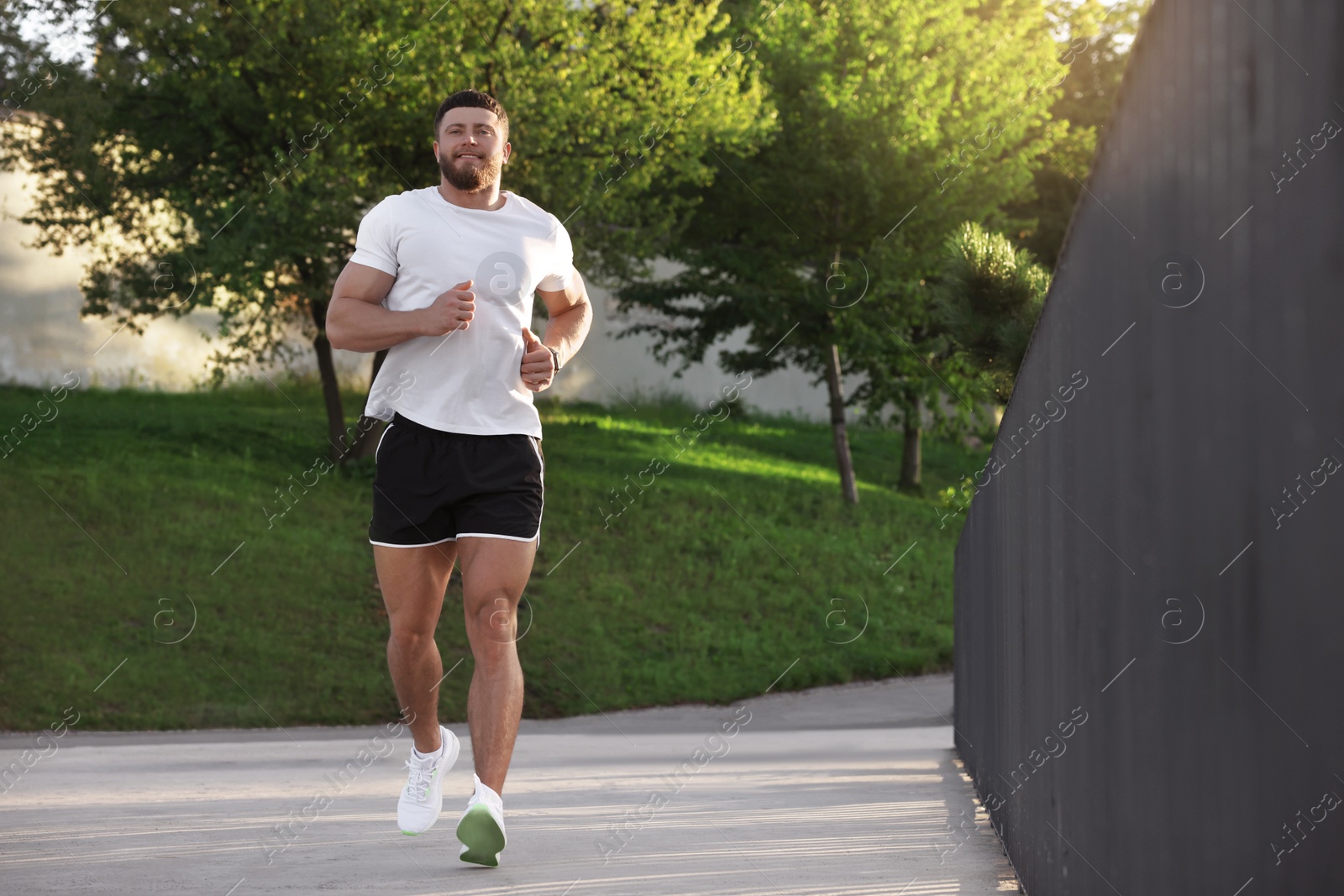 Photo of Young man running outdoors on sunny day. Space for text