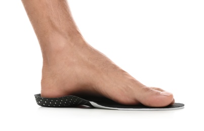 Photo of Man fitting orthopedic insole on white background, closeup. Foot care
