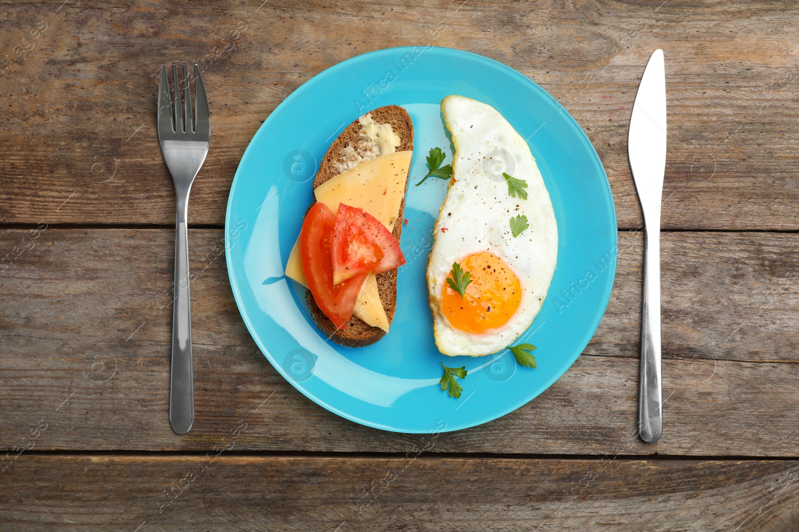 Photo of Fried sunny side up egg and sandwich served on wooden table, flat lay