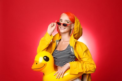 Photo of Beautiful young woman with bright dyed hair and inflatable ring on color background