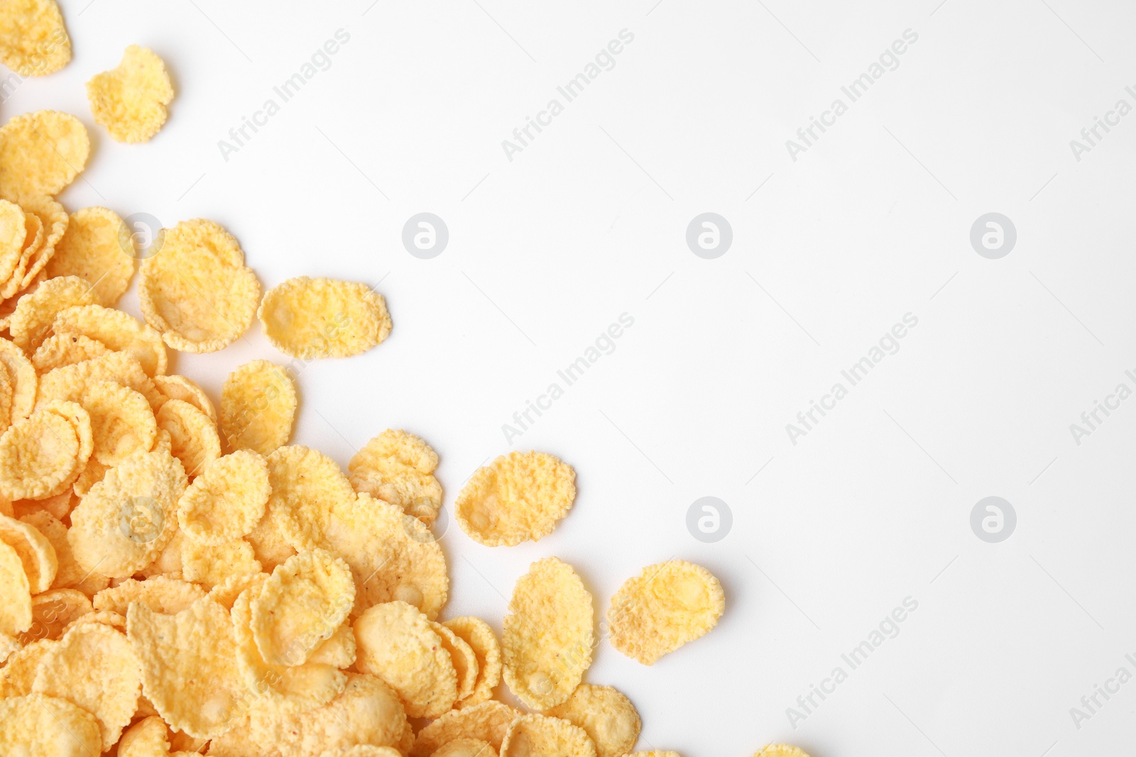 Photo of Breakfast cereal. Tasty corn flakes on white background, flat lay. Space for text