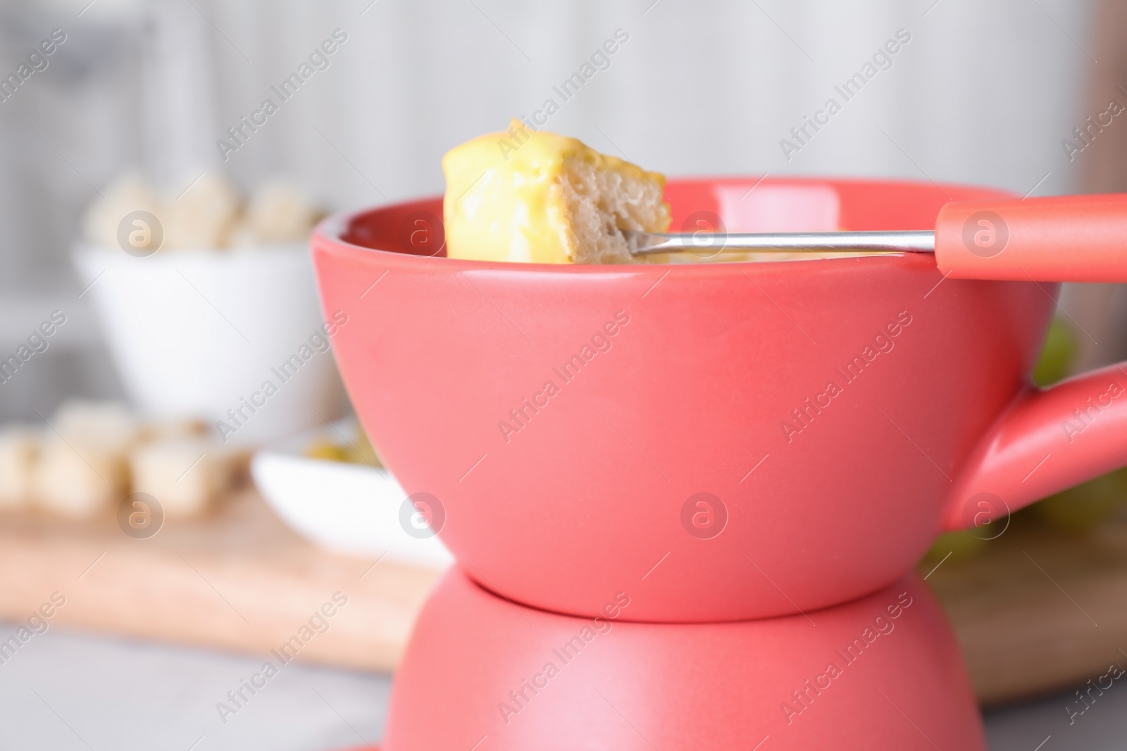 Photo of Pot with delicious cheese fondue and bread on table, closeup