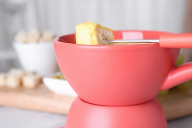 Photo of Pot with delicious cheese fondue and bread on table, closeup