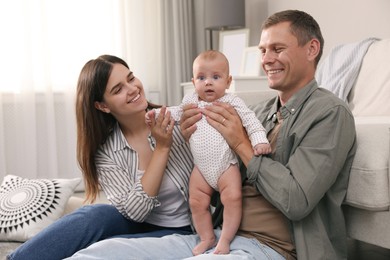 Photo of Happy family with their cute baby on floor in living room
