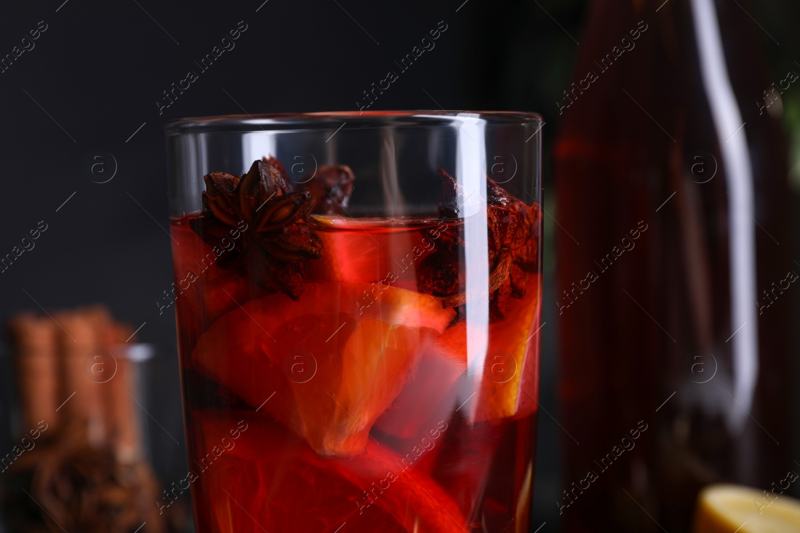 Photo of Glass of aromatic punch drink against dark background, closeup