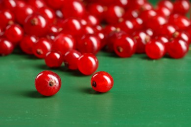 Many ripe red currants on green wooden table, closeup